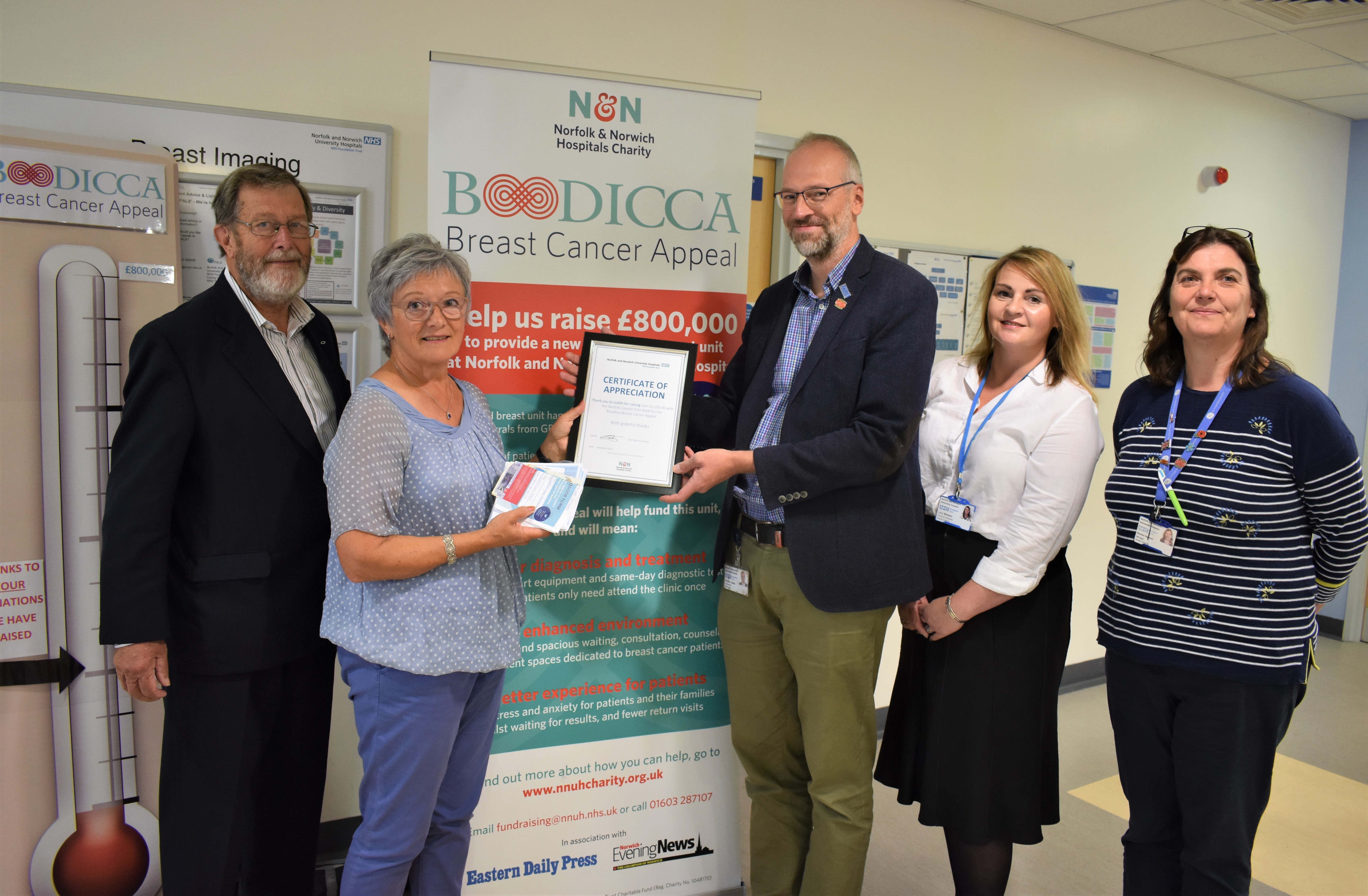 Director of the NNUH Breast Imaging Unit Dr Arne Juette, accompanied by members of his team, presents a Certificate of Appreciation to Judith Marney, and husband John.
